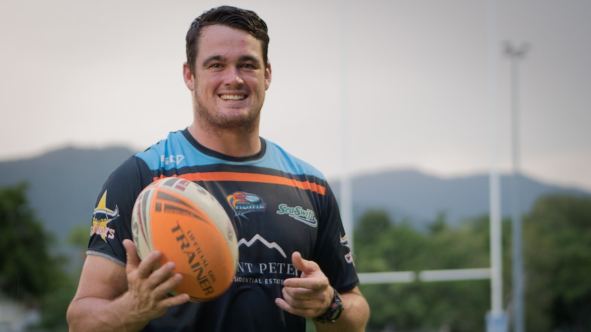 Man with football smiling and standing on field