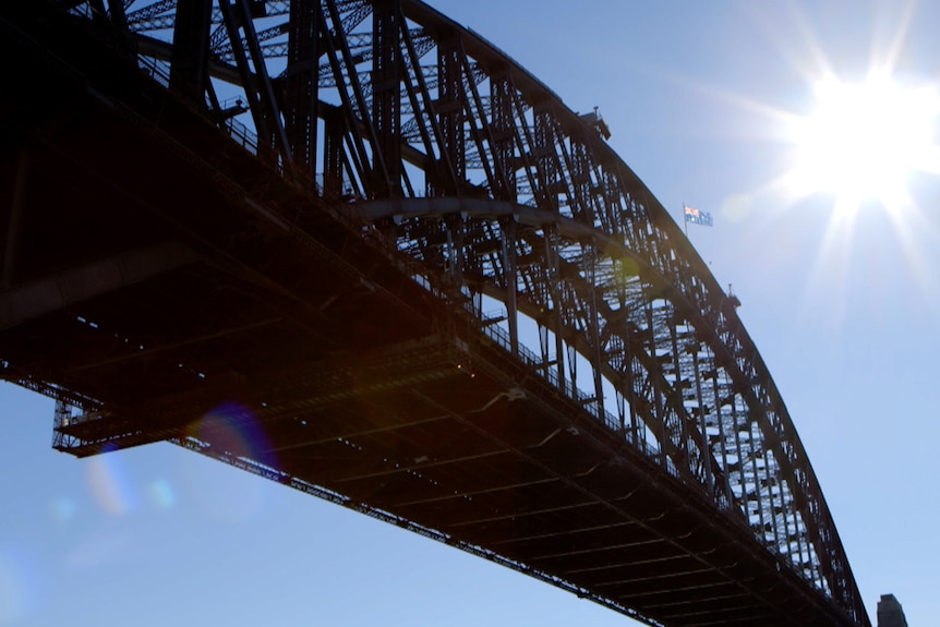 The Sydney Harbour Bridge in silhouette against a blue sky
