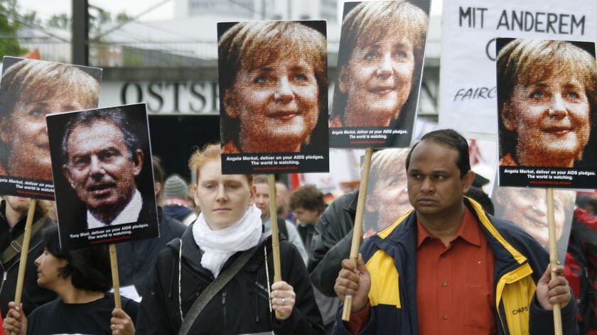 Protesters hold placards with the face of German chancellor Angela Merkel in a anti-G8 march.