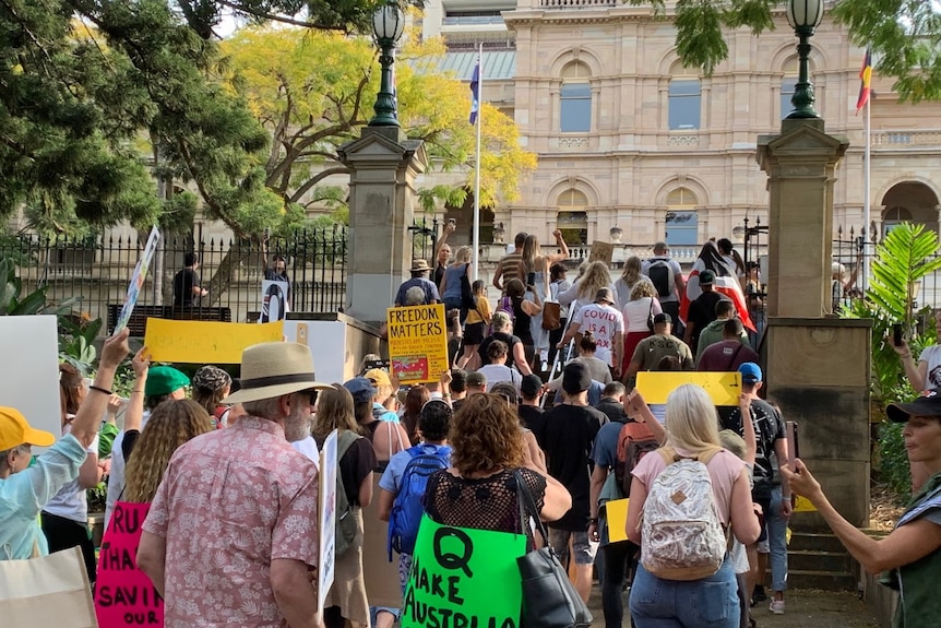 Protesters bearing signs reading 'Freedom Matters' and 'Make Australia Great Again' walk out of Brisbane's botanic gardens.