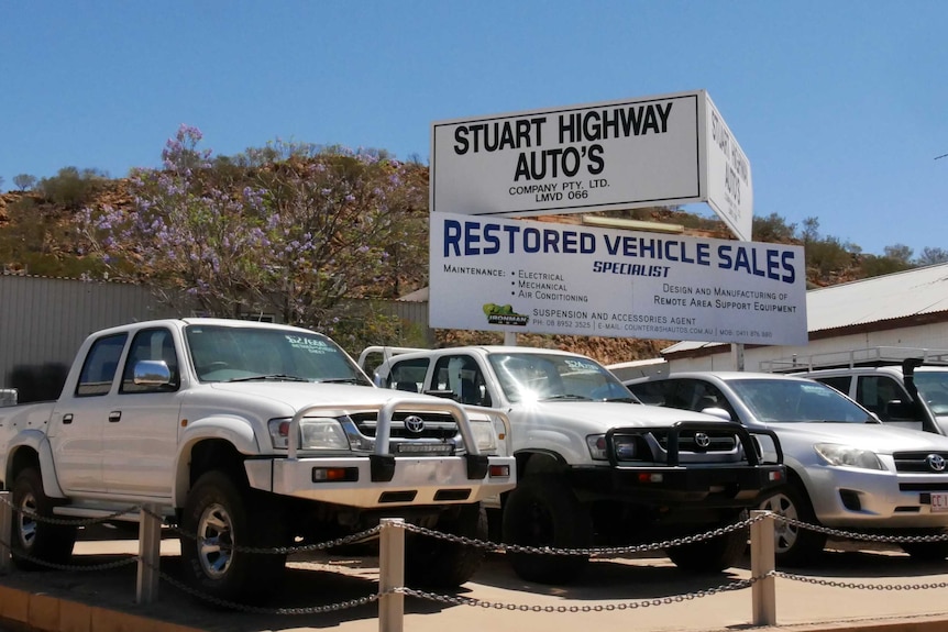 three four wheel drive vehicles on a car yard lot with the sign for the business in the bcakground