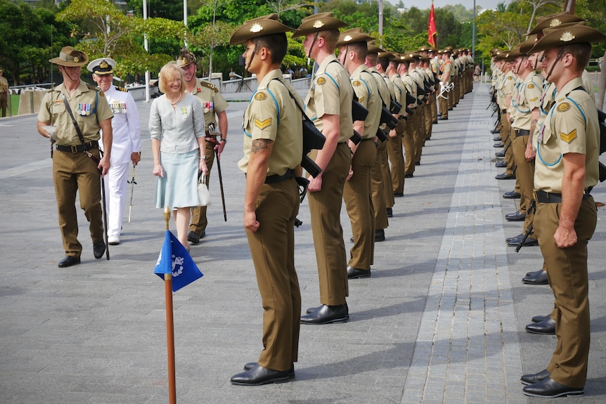 A woman walks past a guard of honour