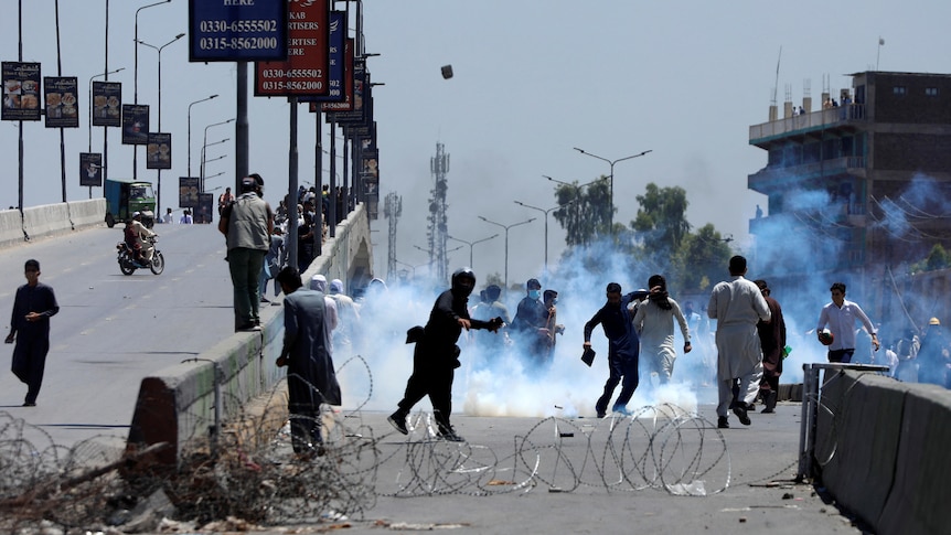 People stand on the streets of Pakistan throwing smoke bombs.