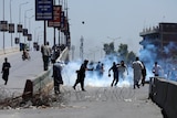 People stand on the streets of Pakistan throwing smoke bombs.