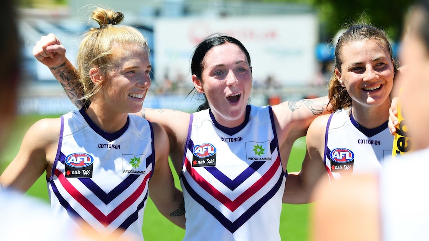 Sabreena Duffy shouts with her arms around Fremantle Dockers teammates after their AFLW win over Adelaide.