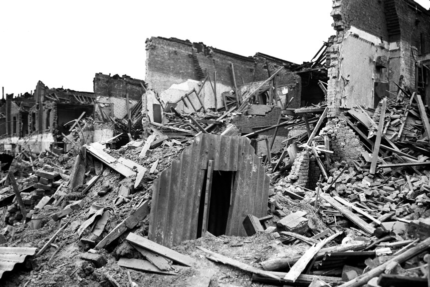 A corrugated iron doorway rises from the debris of a bombed neighbourhood 