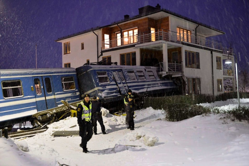 Policemen stand in front of a local train that derailed into a residential building in Saltsjoebaden, Sweden.