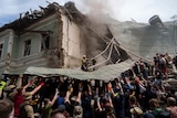 Dozens of people holding up the roof of a building crumbling down after a missile strike 