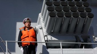 A Chinese naval officer stands on a warship.