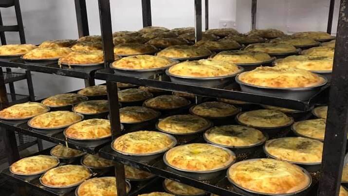 Stacks of quiches on shelves in a bakery.