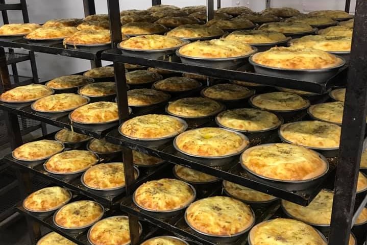 Stacks of quiches on shelves in a bakery.