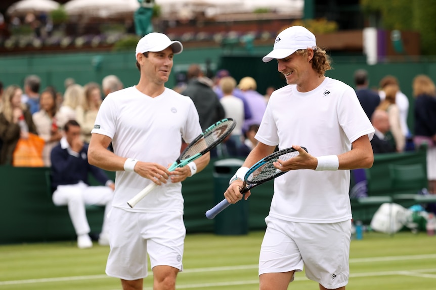 Max Purcell and Matt Ebden smile and converse on-court at Wimbledon