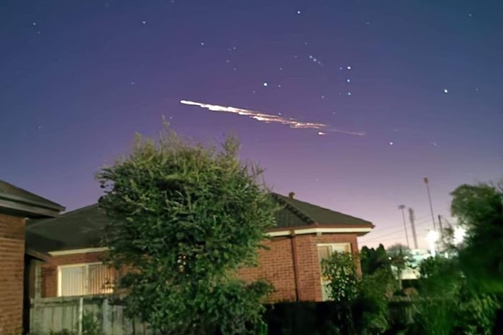 A suburban house in Devonport with a white, streaky light in the night sky above it.