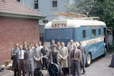 A group of men stand in front of a blue van marked "ABC-TV".