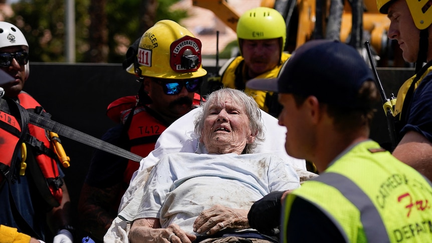 Elderly woman on a stretcher being cared for by firefighters
