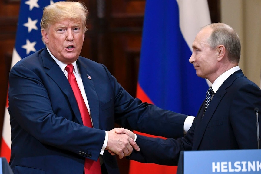 Donald Trump shakes hands with Vladimir Putin, both standing in front of US and Russian flags with a lectern labelled 'Helsinki'