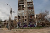 A view shows a residential building damaged by a military strike.