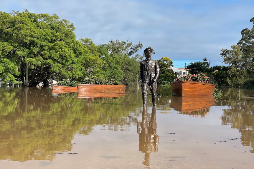 Water surrounding a male WWI statue and boats filled with flowers in a park