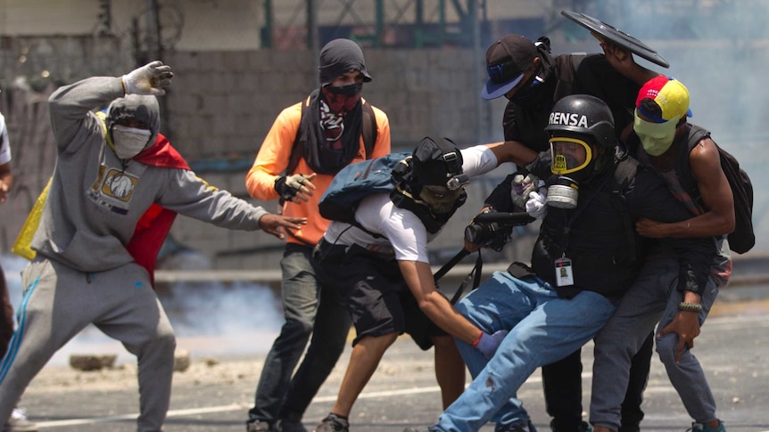 Venezuelan protesters help an injured journalist