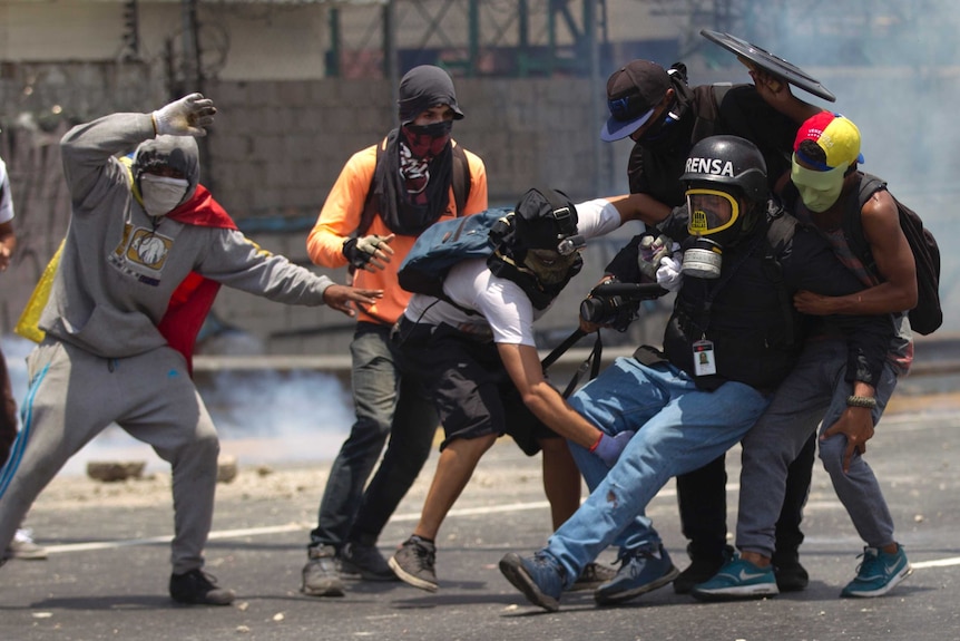 Venezuelan protesters help an injured journalist