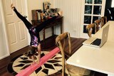 Child doing gymnastics in front of her computer
