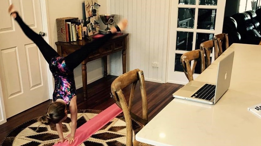 Child doing gymnastics in front of her computer