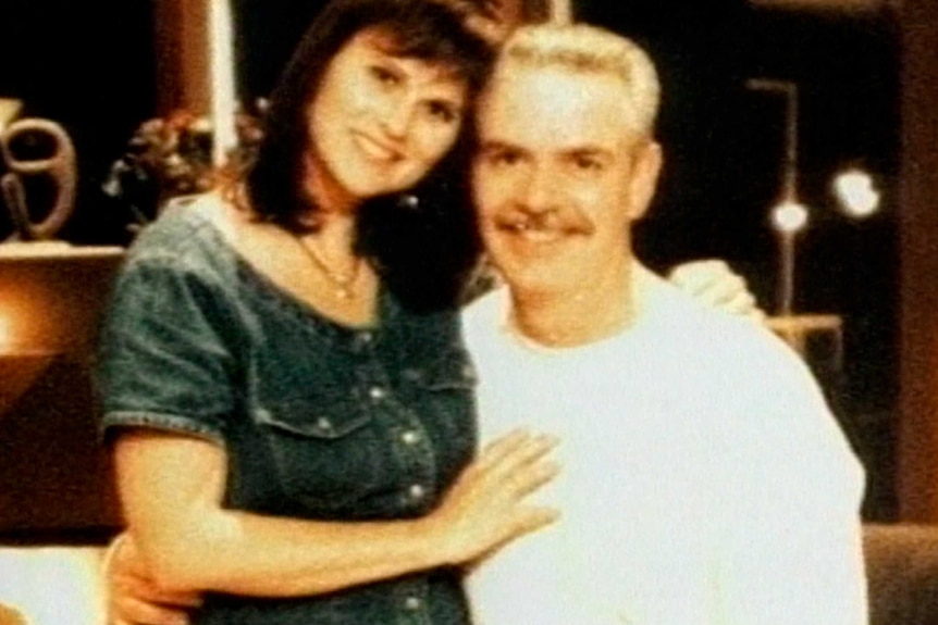 A man with a white t-shirt hugs a woman in a denim dress in an archive family photo.