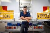 A man leans against the back of a semi-trailer.