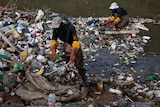 people with gloves pick up rubbish from a polluted river in Tembisa
