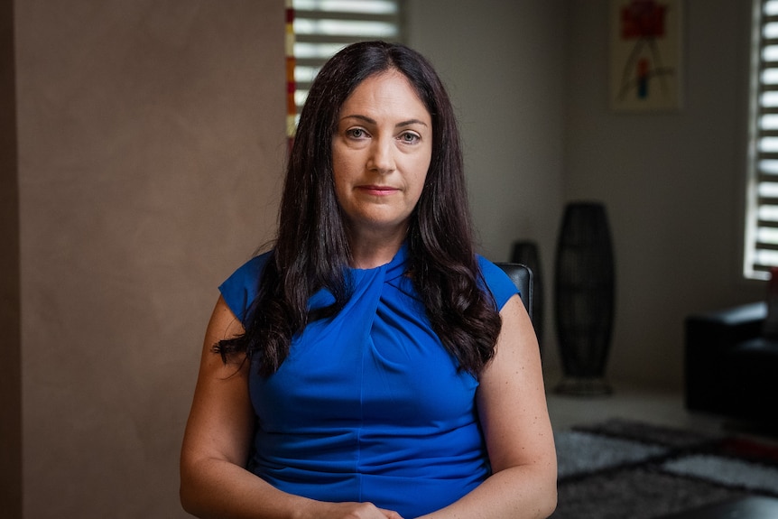 A woman wearing a blue dress looking serious