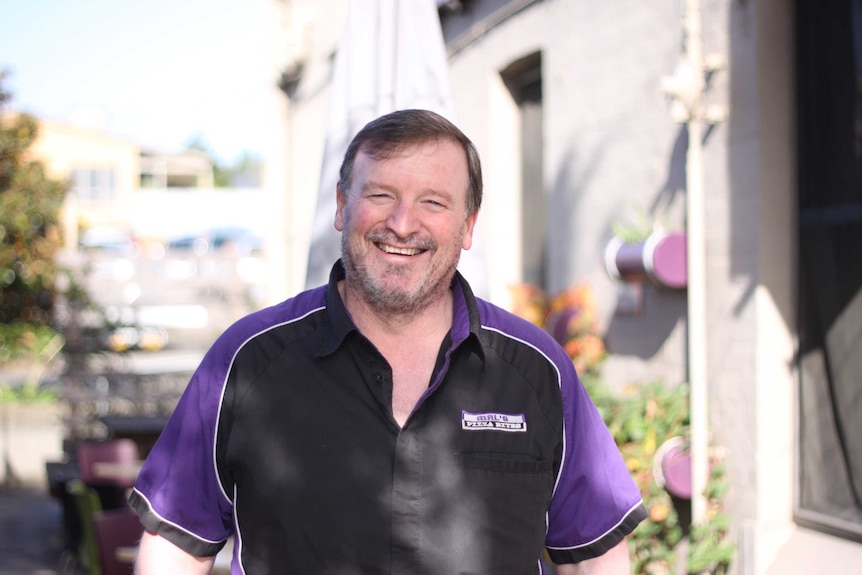 Closeup of a middle aged man standing outside in a courtyard.