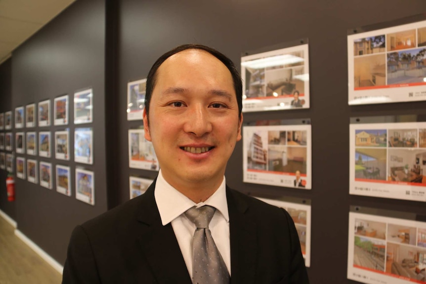 A real estate agent in front of a window display of houses for sale