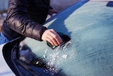 Man scraping ice from the windshield.