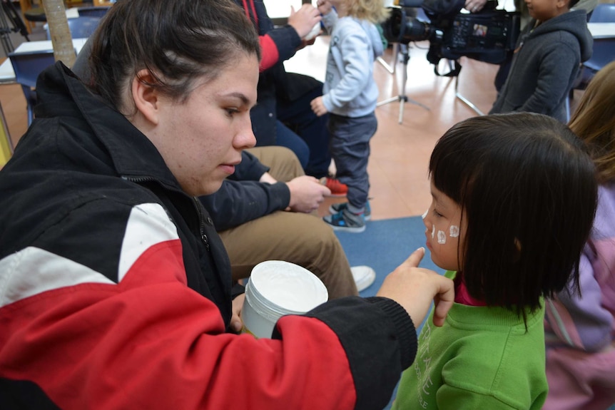 Nakiya Smith face painting a Hawker pre-school student