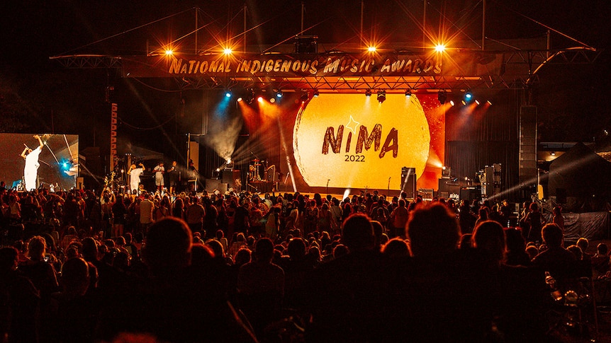 Long shot from the back of the NIMAs stage 2022, people in audience cheer