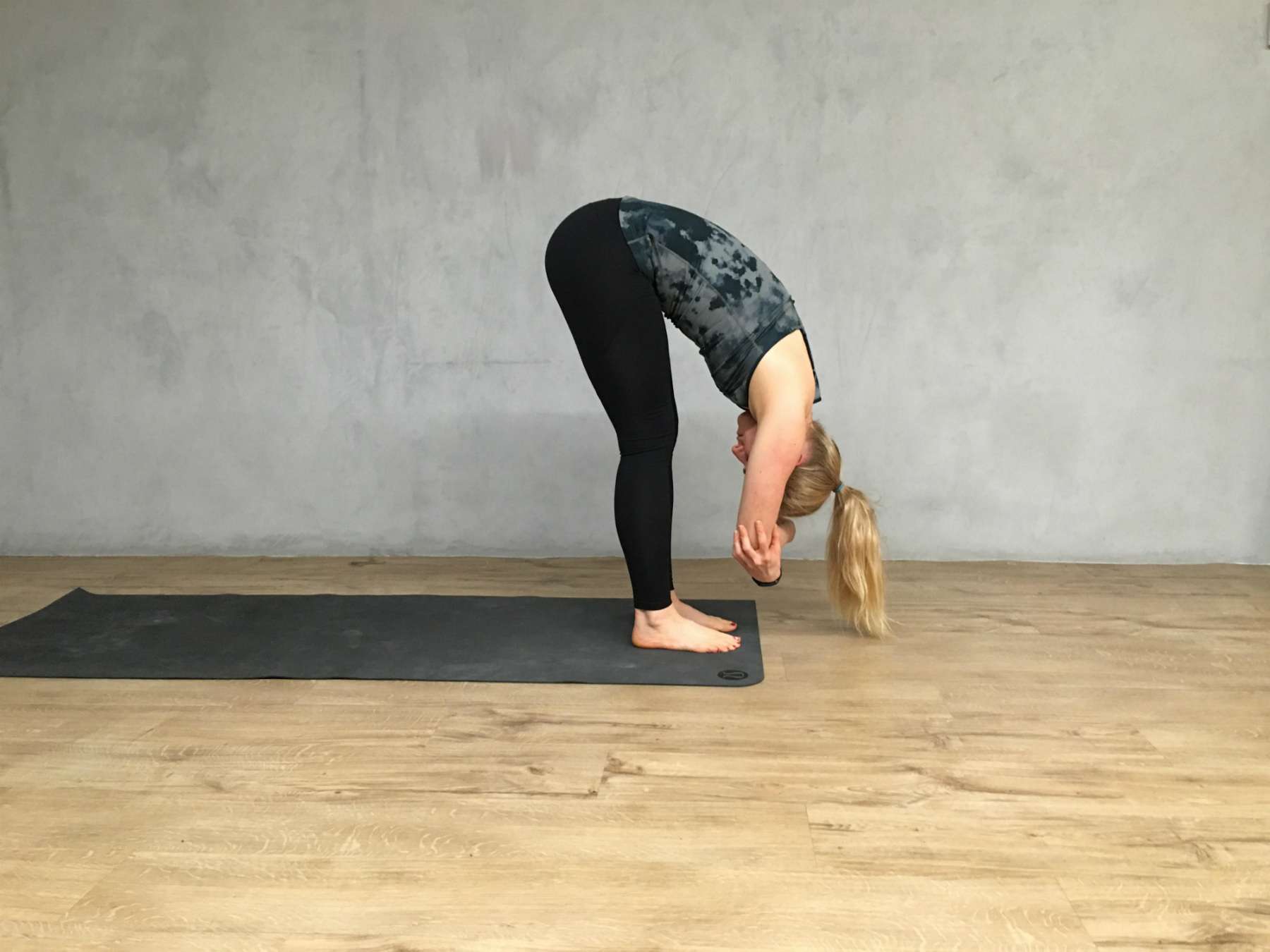 Ein Yogalehrer demonstriert die Vorwärtsbeuge im Stehen.