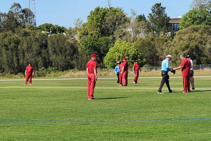 Uniformed players on a cricket pitch during a match.