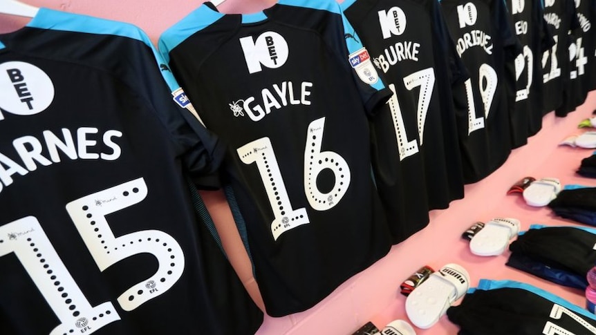 Shirts of West Bromwich football players hanging on a pink wall