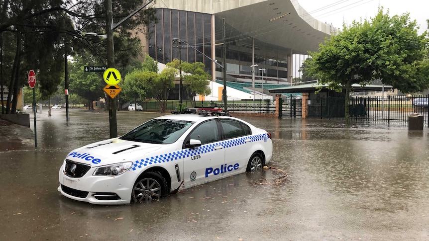 A police ca parked in the middle of the street in Glebe, Sydney, as torrential rain pours down on the city.
