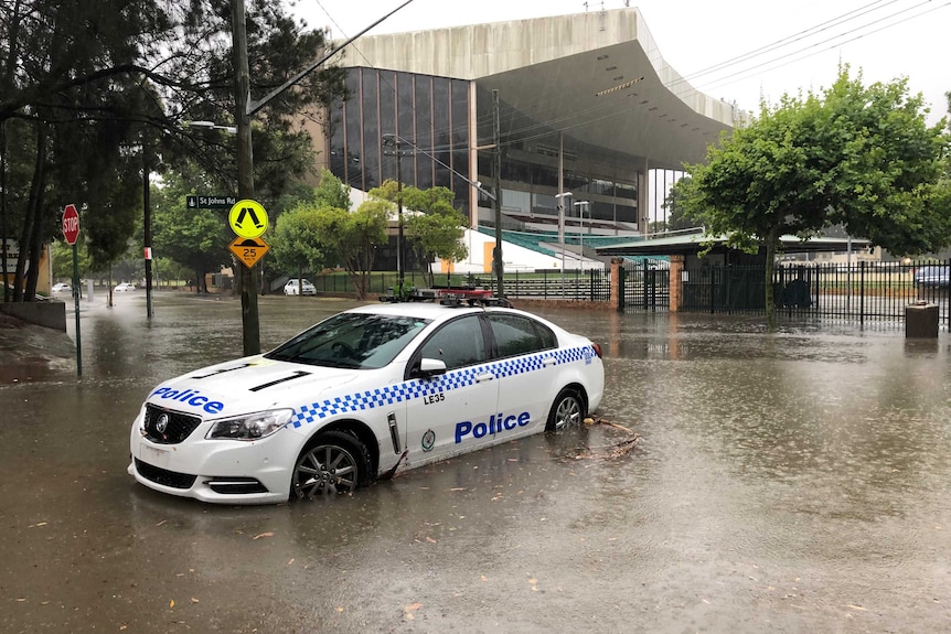 A police ca parked in the middle of the street in Glebe, Sydney, as torrential rain pours down on the city.