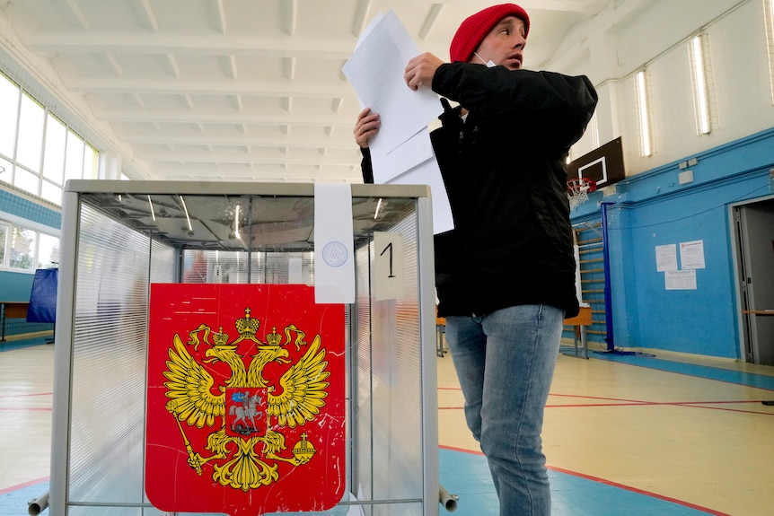 A man casts his ballots into a clear box.