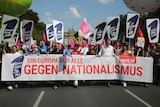 People walk in the street behind a large banner reading 'A Europe for all against nationalism'.