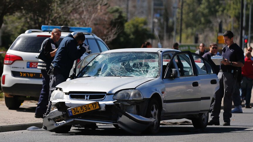 Israeli policemen inspect the car used to ram into a group of pedestrians
