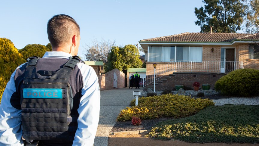 A police officer stands in front of a home.