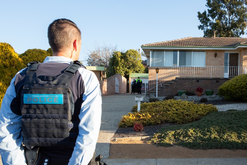 A police officer stands in front of a home.