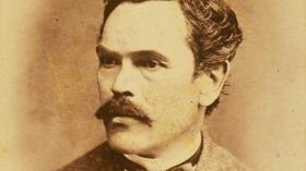 A sepia head shot of a man with short dark hair and a mustache.