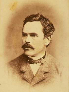 A sepia head shot of a man with short dark hair and a mustache.