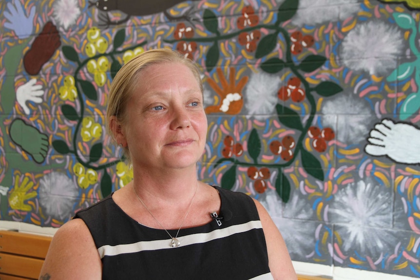 Outreach worker Pauline Reynolds stands in front of a mural in Tennant Creek.