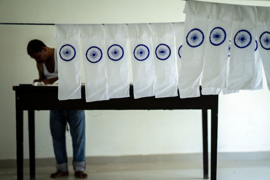 A row of white bands with a blue wheel imprinted on them hanging on a line with a man in the background.