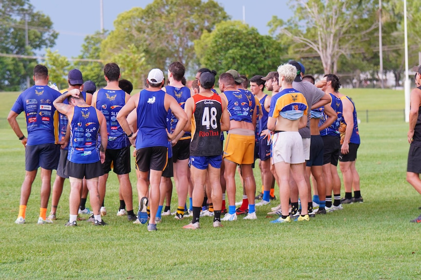 A group of young men stand crowded together on a football team. 